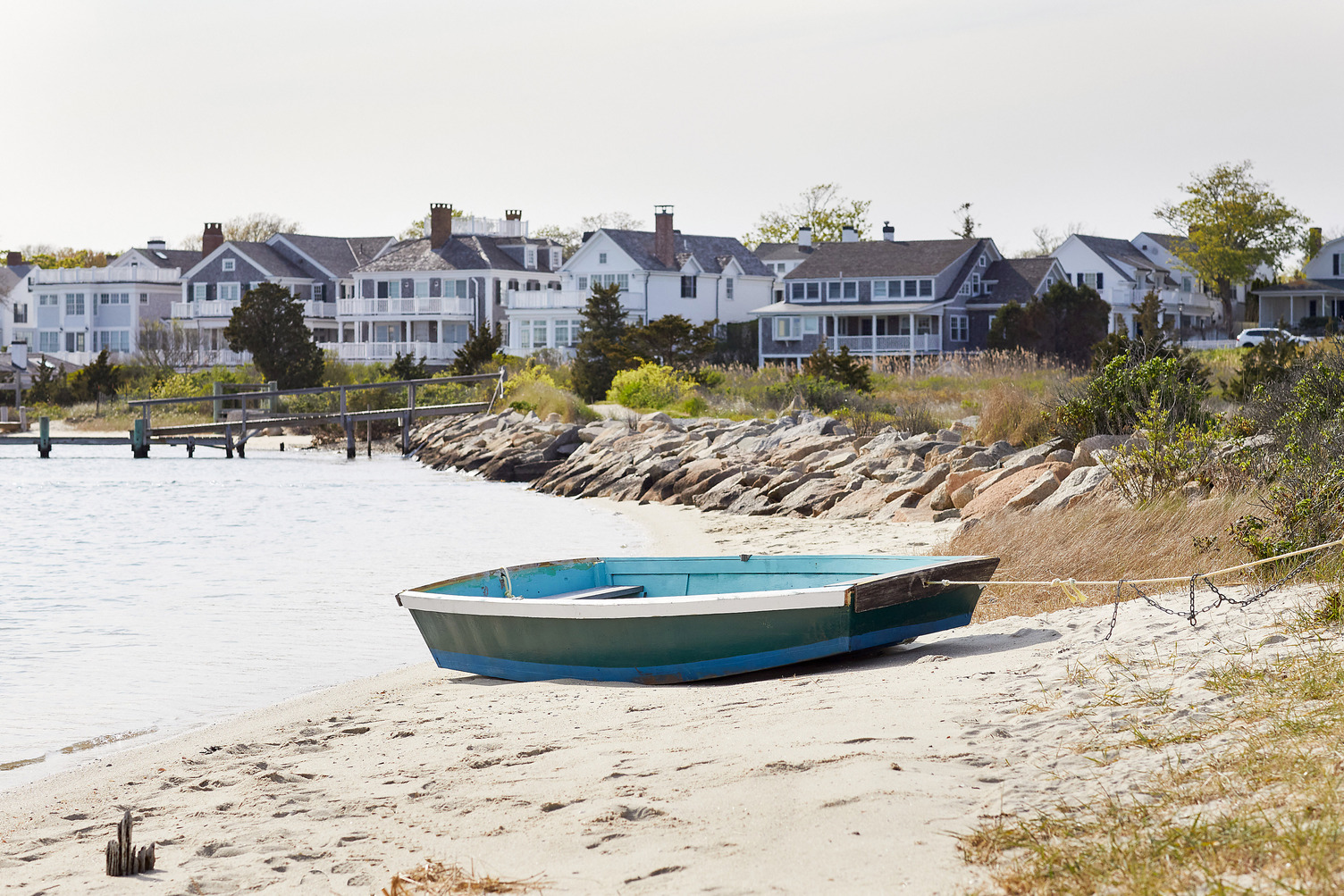 A rowboat tied up and sitting on the sand at a beach